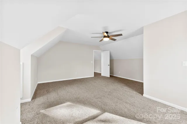 an empty room with a ceiling fan and carpet