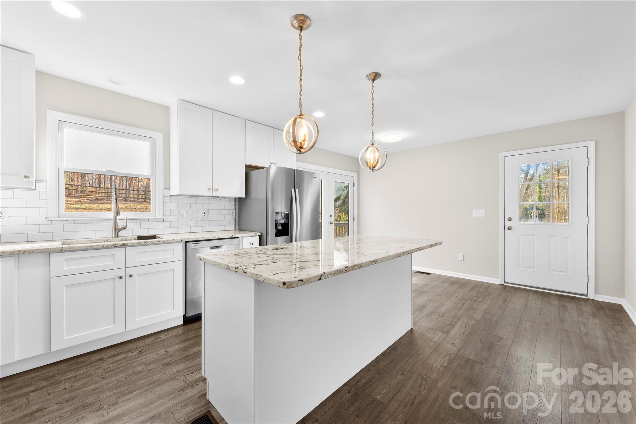 16218 Barbee Road Stanfield, NC 28163 - Photo 9 of 30 a kitchen with granite countertop a stove a sink and white cabinets with wooden floor