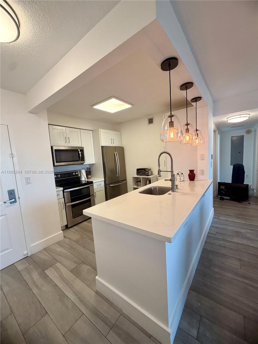 900 Southwest 8th Street, Unit 1509 Miami, FL 33130 - Photo 11 of 37 a large white kitchen with wooden floor and stainless steel appliances