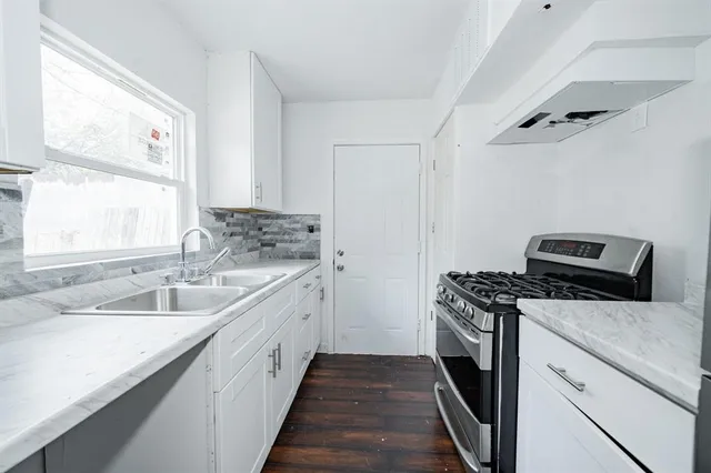 a kitchen with a sink stove top oven and cabinets
