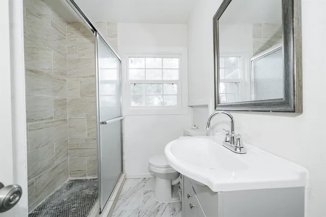 a bathroom with a sink a toilet and shower