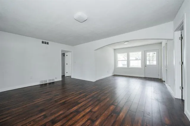 a view of an empty room with wooden floor and window
