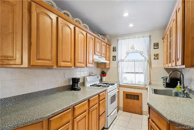 a kitchen with stainless steel appliances a sink a stove a refrigerator cabinets and a window