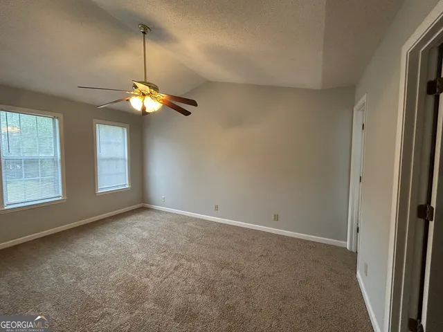 an empty room with windows and fan