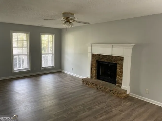 an empty room with wooden floor fireplace and windows