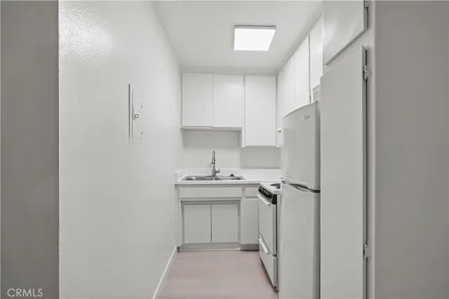 a kitchen with a sink a refrigerator and cabinets