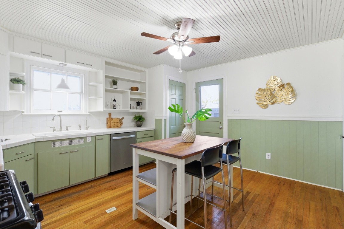 1506 Grace Street Taylor, TX 76574 - Photo 7 of 21 Kitchen featuring green cabinetry, a wainscoted wall, stainless steel appliances, light wood-type flooring, and open shelves