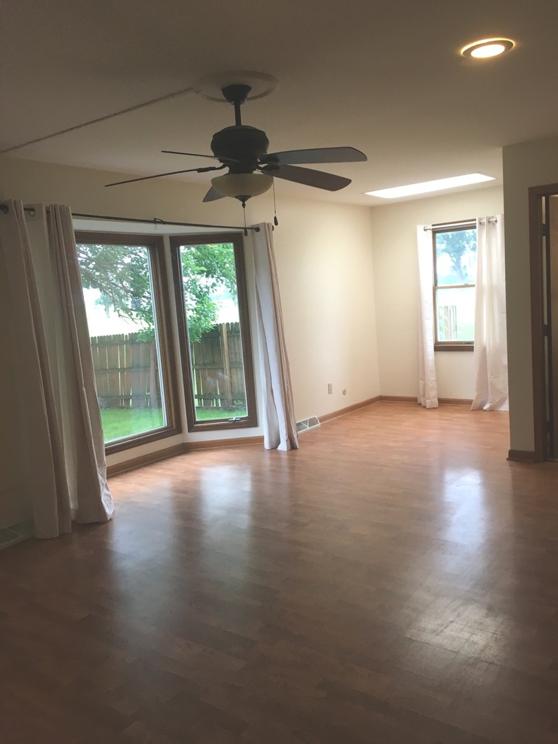 13078 Church Road Yorkville, IL 60560 - Photo 6 of 22 a view of a livingroom with wooden floor a ceiling fan and windows
