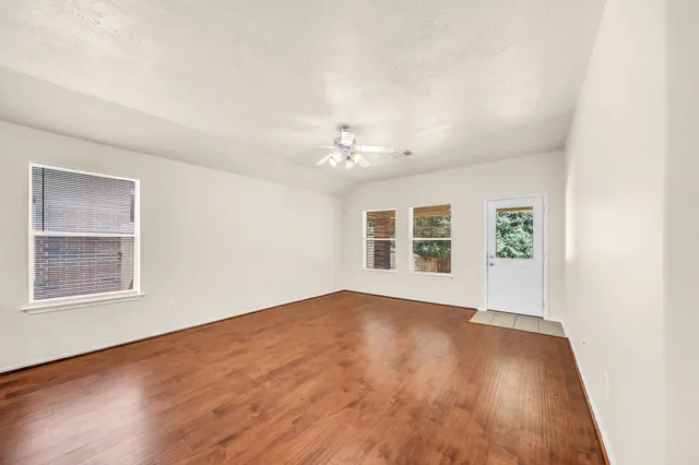 an empty room with wooden floor and windows