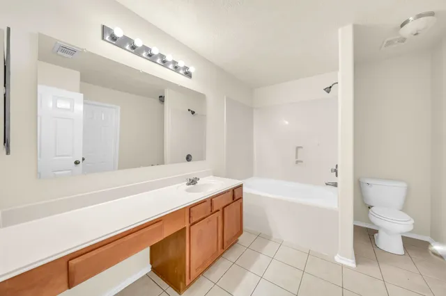 a spacious bathroom with a bathtub shower sink mirror and toilet