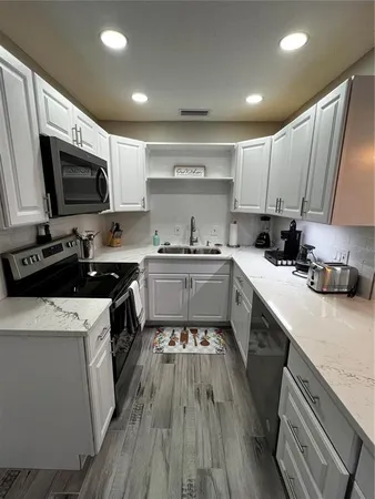 a kitchen with a sink a stove top oven a refrigerator cabinets and a window
