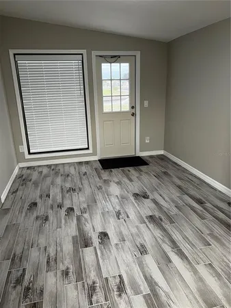 an empty room with wooden floor and windows