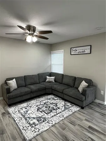 a living room with furniture and a ceiling fan
