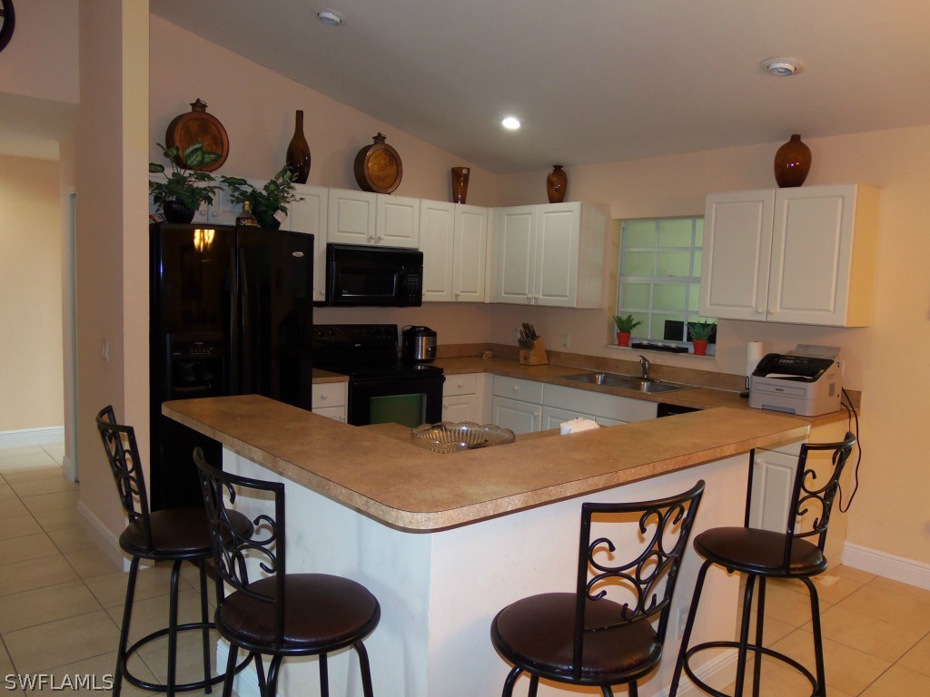 462 Rajah Street Lehigh Acres, FL 33974 - Photo 5 of 17 a kitchen with stainless steel appliances a sink a stove a table and chairs