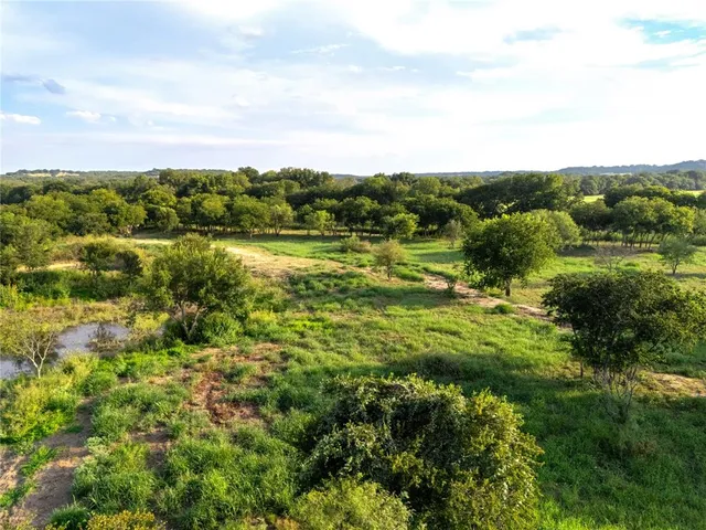 an aerial view of residential houses with outdoor space and trees