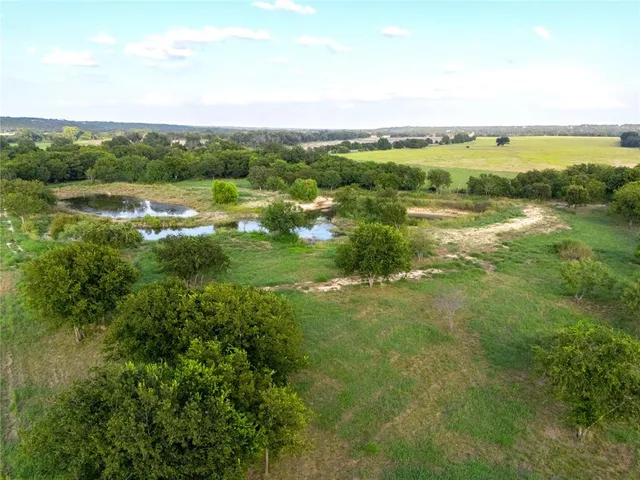 an aerial view of residential houses with outdoor space and trees
