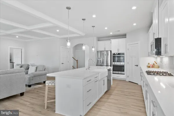 a large white kitchen with lots of counter space wooden floor and appliances