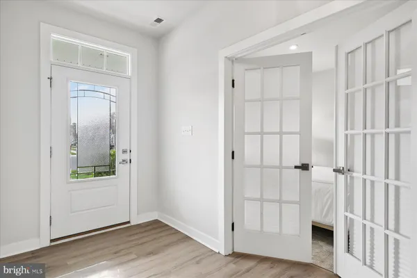 an empty room with wooden floor mirror and windows