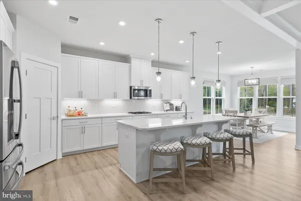 a kitchen with counter space sink refrigerator dining table and chairs