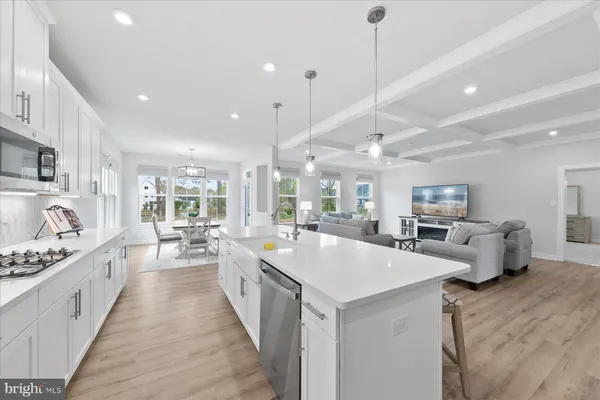 a large white kitchen with kitchen island a stove a sink a center island and furniture