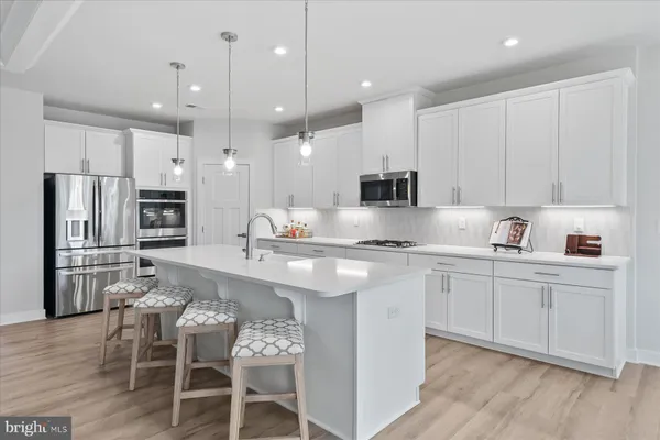 a kitchen with stainless steel appliances kitchen island granite countertop a sink refrigerator and cabinets