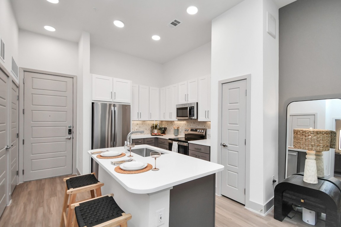 1617 Enid Street, Unit 318 Houston, TX 77009 - Photo 7 of 50 a kitchen that has a sink a refrigerator and a stove top oven with wooden floor