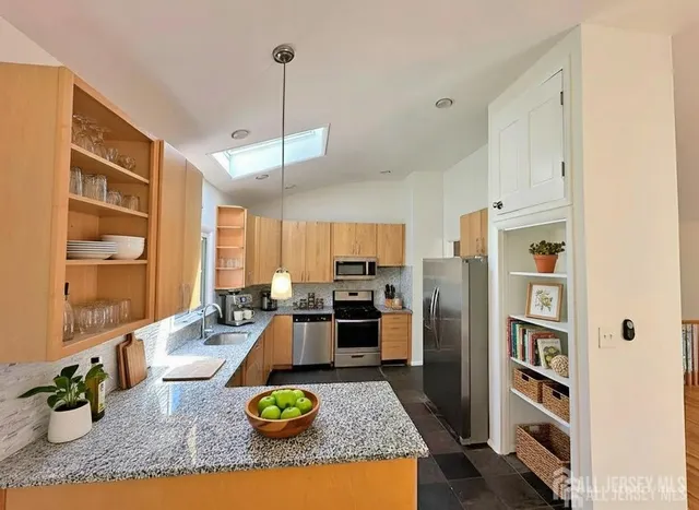 a kitchen with stainless steel appliances granite countertop a refrigerator a stove and a sink with wooden floor