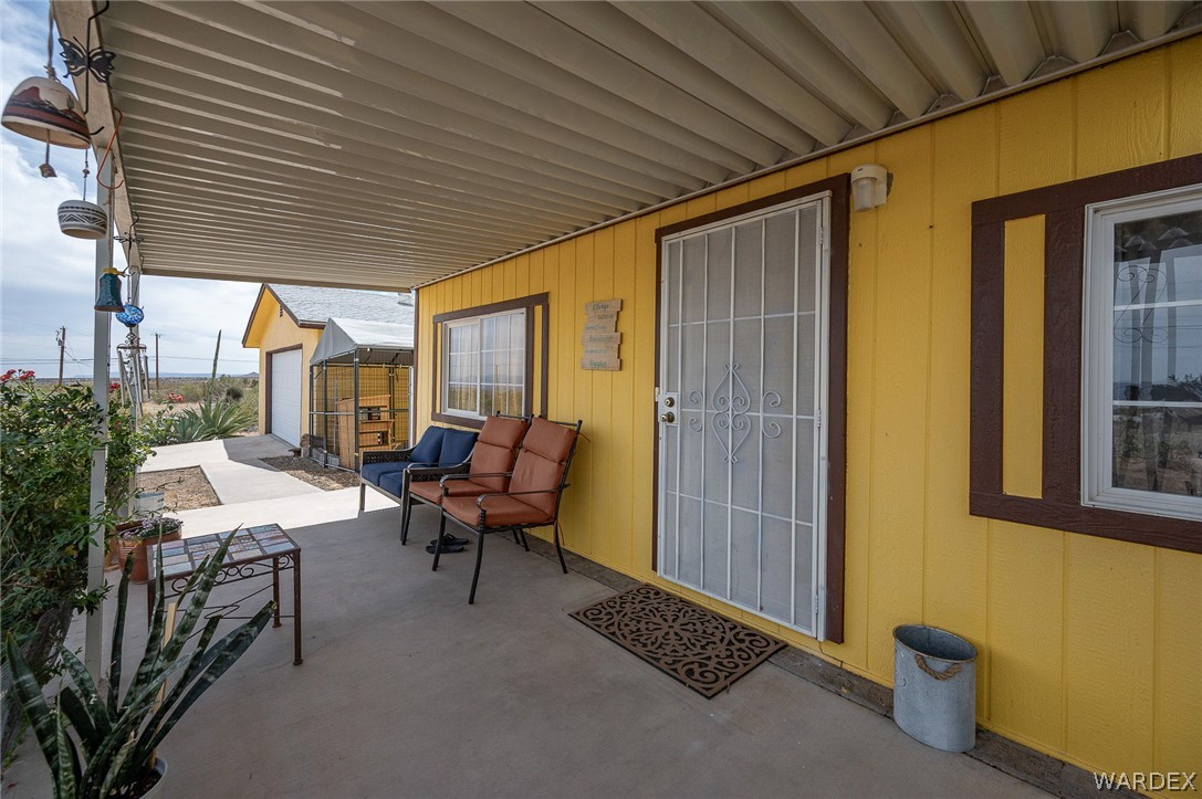 2465 Egar Road Golden Valley, AZ 86413 - Photo 14 of 98 The property features a covered porch with a concrete floor, a yellow exterior, and a security screen door