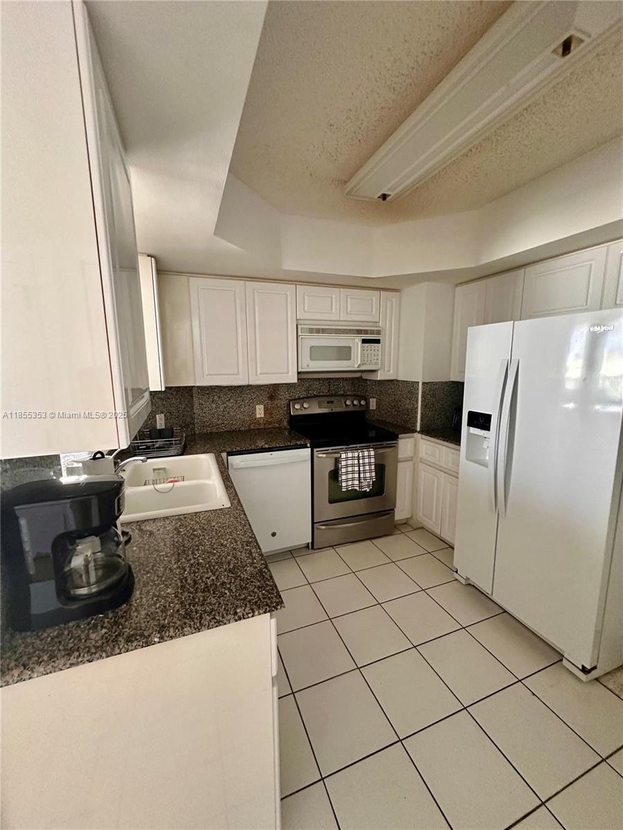 6301 Collins Avenue, Unit 806 Miami Beach, FL 33141 - Photo 6 of 26 a kitchen with stainless steel appliances granite countertop a stove a sink and a refrigerator