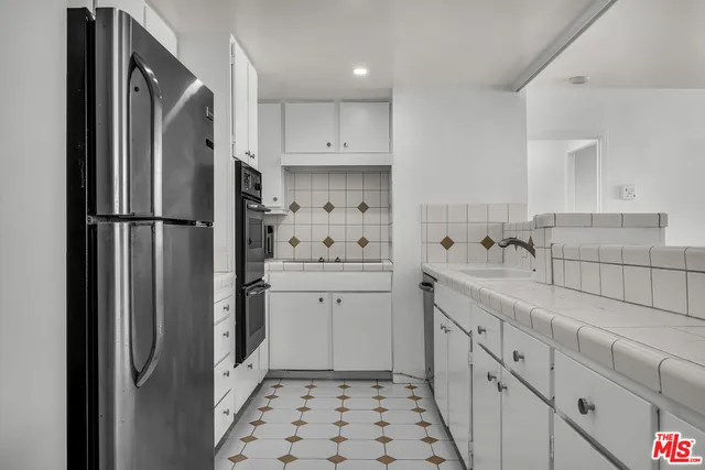 a kitchen with sink a refrigerator and cabinets