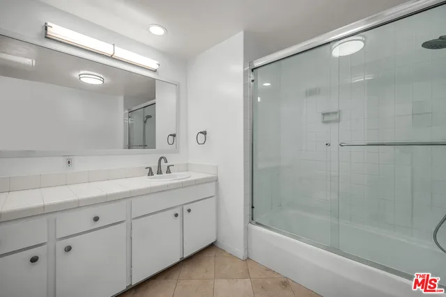 a bathroom with a bathtub shower sink vanity and mirror