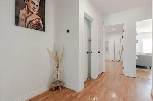 a view of a hallway with wooden floor and a bathroom