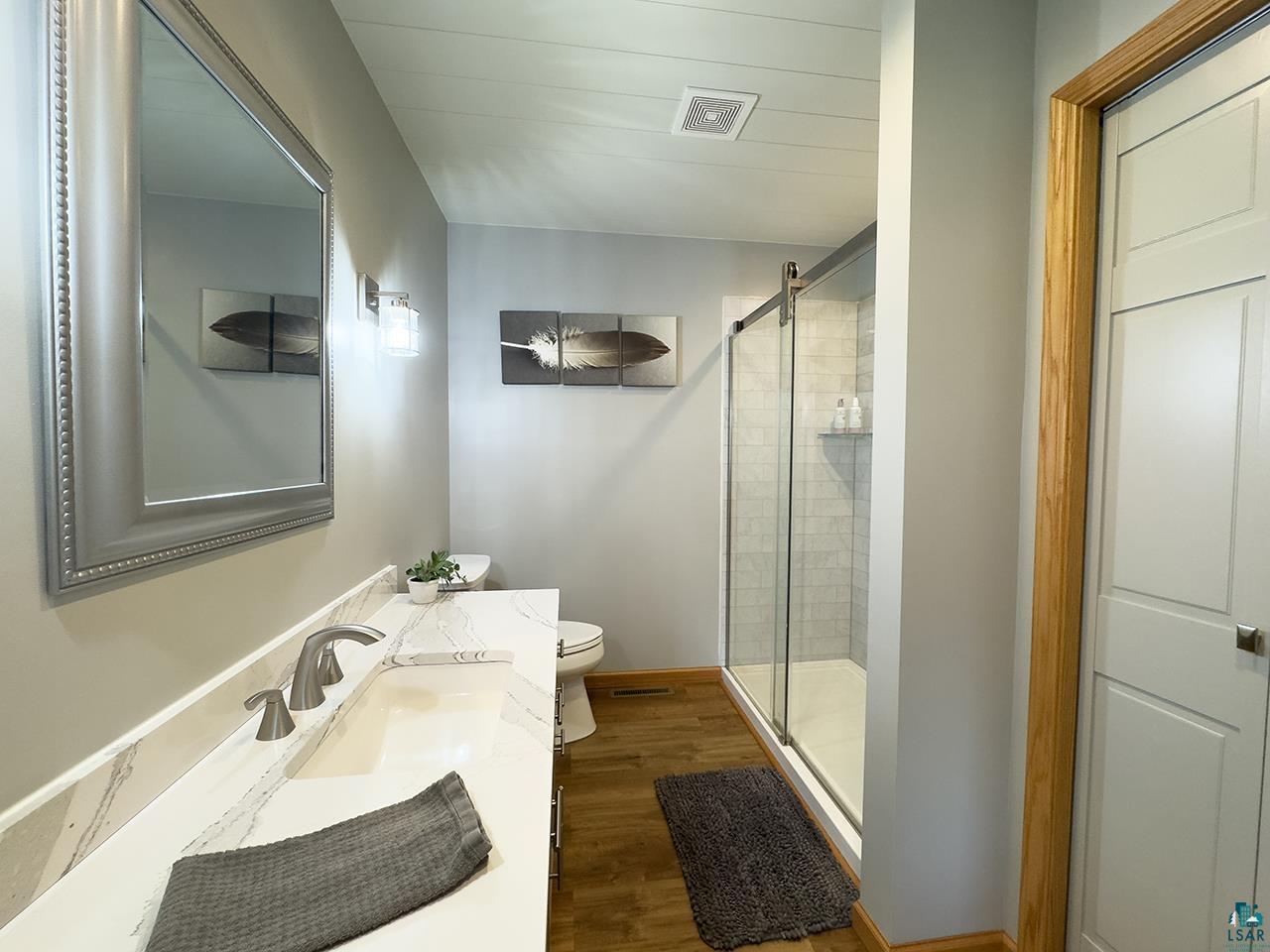 197 Jefferson Street Buhl, MN 55713 - Photo 11 of 31 Full bath with toilet, a shower stall, wood finished floors, and vanity