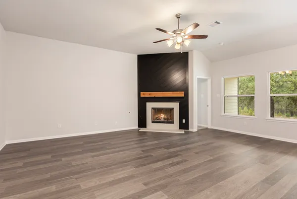 a view of an empty room with wooden floor fireplace and a window
