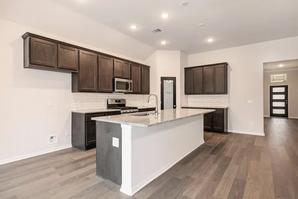 a kitchen with stainless steel appliances a stove top oven a sink a refrigerator white cabinets and wooden floor