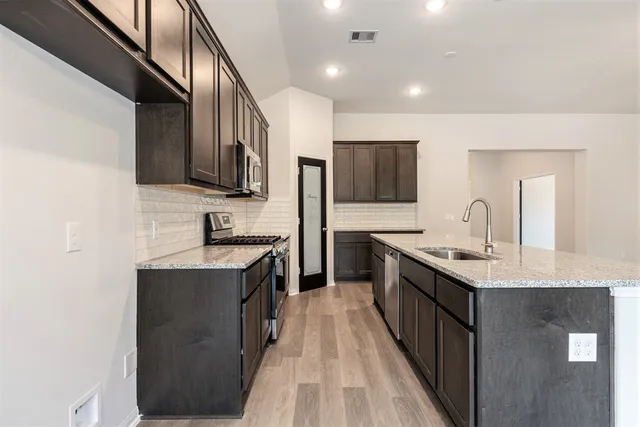 a kitchen with stainless steel appliances granite countertop a sink stove and refrigerator