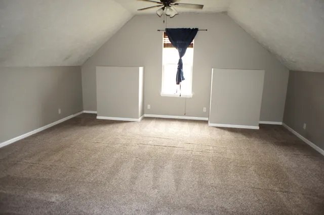 an empty room with a window and a ceiling fan