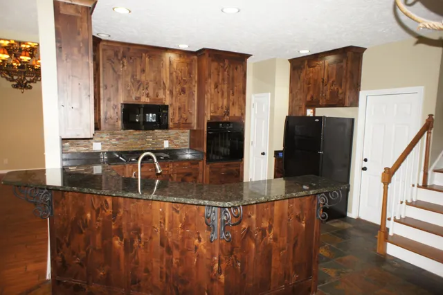 a kitchen with stainless steel appliances granite countertop a refrigerator a stove and a sink with wooden floor