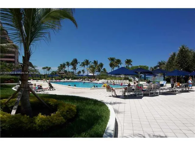 a view of swimming pool with outdoor seating and trees in the background