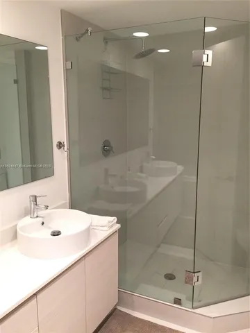 a bathroom with a sink shower and a mirror