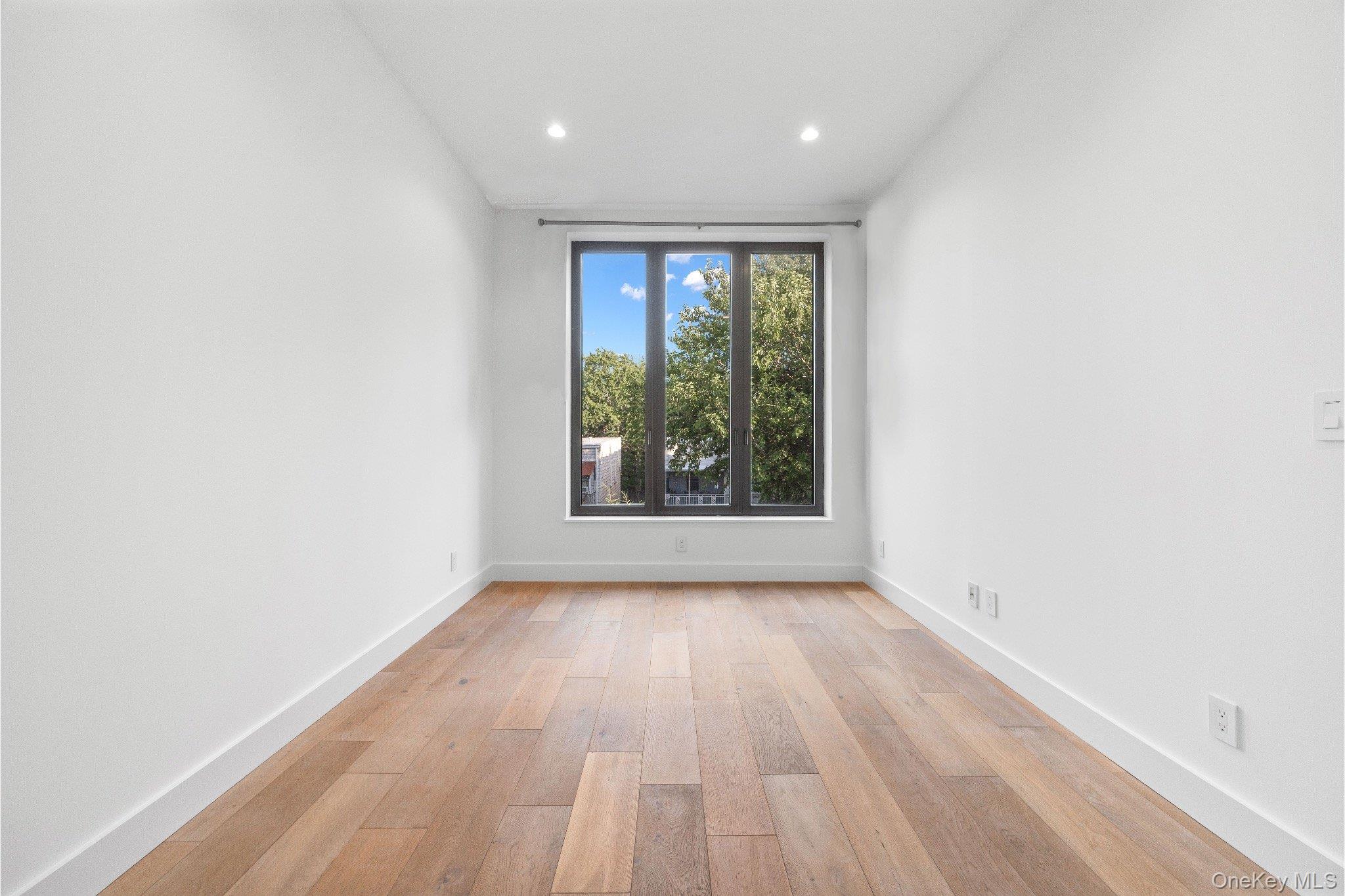 26-33 28th Street, Unit 3B Queens, NY 11102 - Photo 11 of 16 an empty room with wooden floor and windows