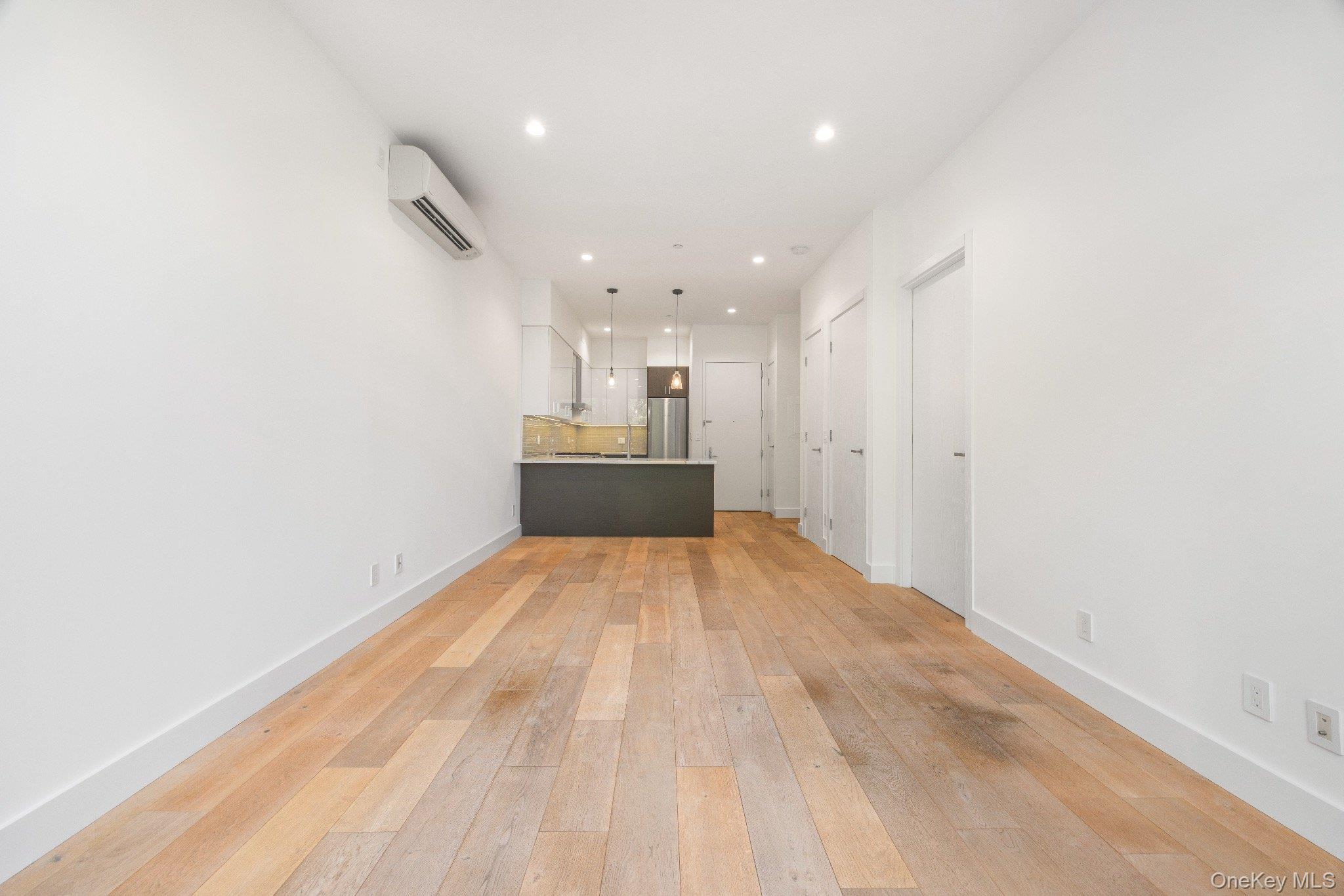 26-33 28th Street, Unit 3B Queens, NY 11102 - Photo 9 of 16 an empty room with kitchen and windows