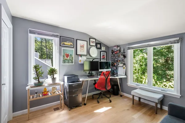 a bedroom with a bed lamp and a large window with potted plants