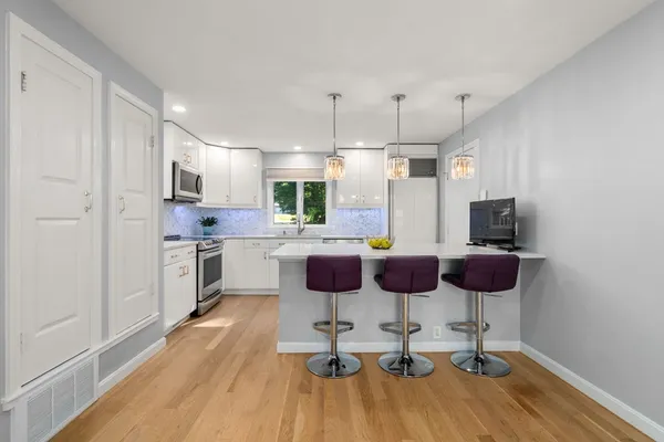 a kitchen with stainless steel appliances kitchen island granite countertop a dining table chairs and a refrigerator