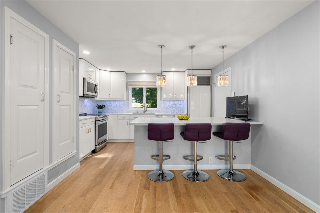 16 Coltsway, Unit 16 Wayland, MA 01778 - Photo 8 of 29 a kitchen with stainless steel appliances kitchen island granite countertop a dining table chairs and a refrigerator
