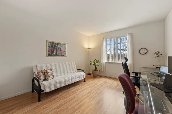 a bedroom with a bed painting on wall and a large window