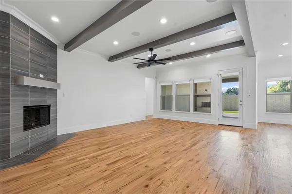 a view of an empty room with wooden floor fireplace and a window