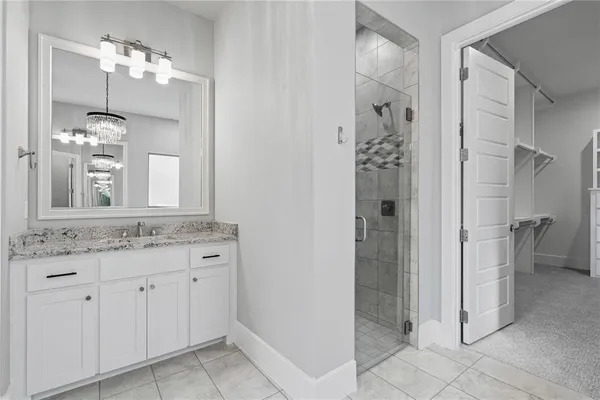 a bathroom with a granite countertop sink two mirror and a shower