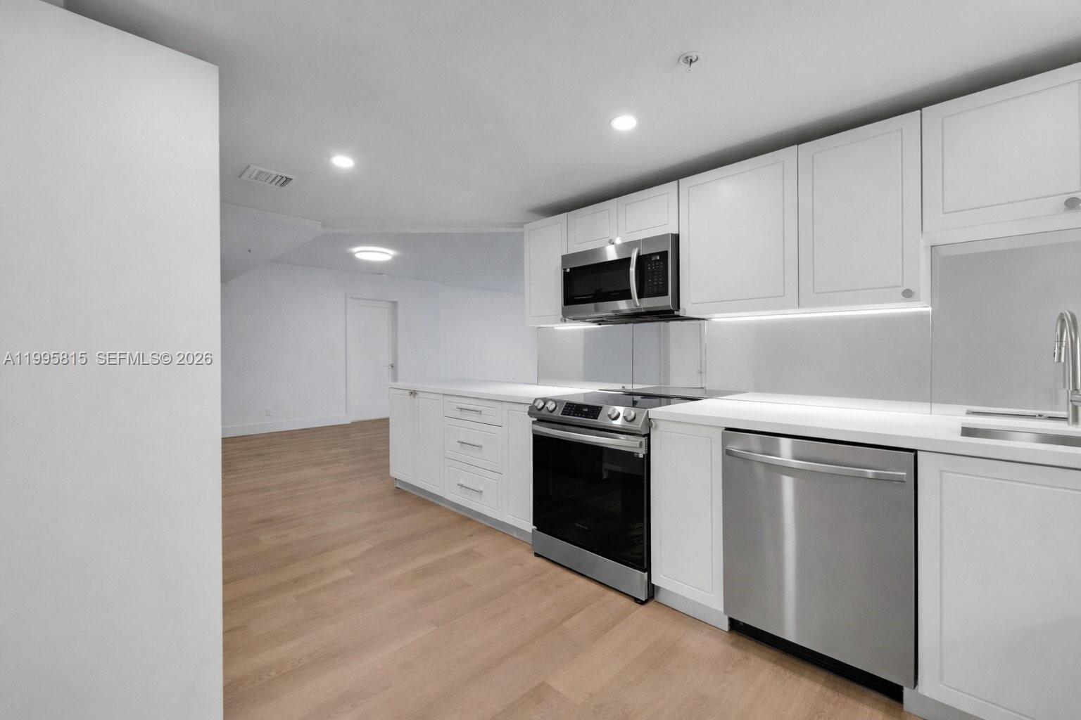 555 Northeast 34th Street, Unit 204 Miami, FL 33137 - Photo 11 of 31 a kitchen with stainless steel appliances granite countertop a stove a sink and a microwave