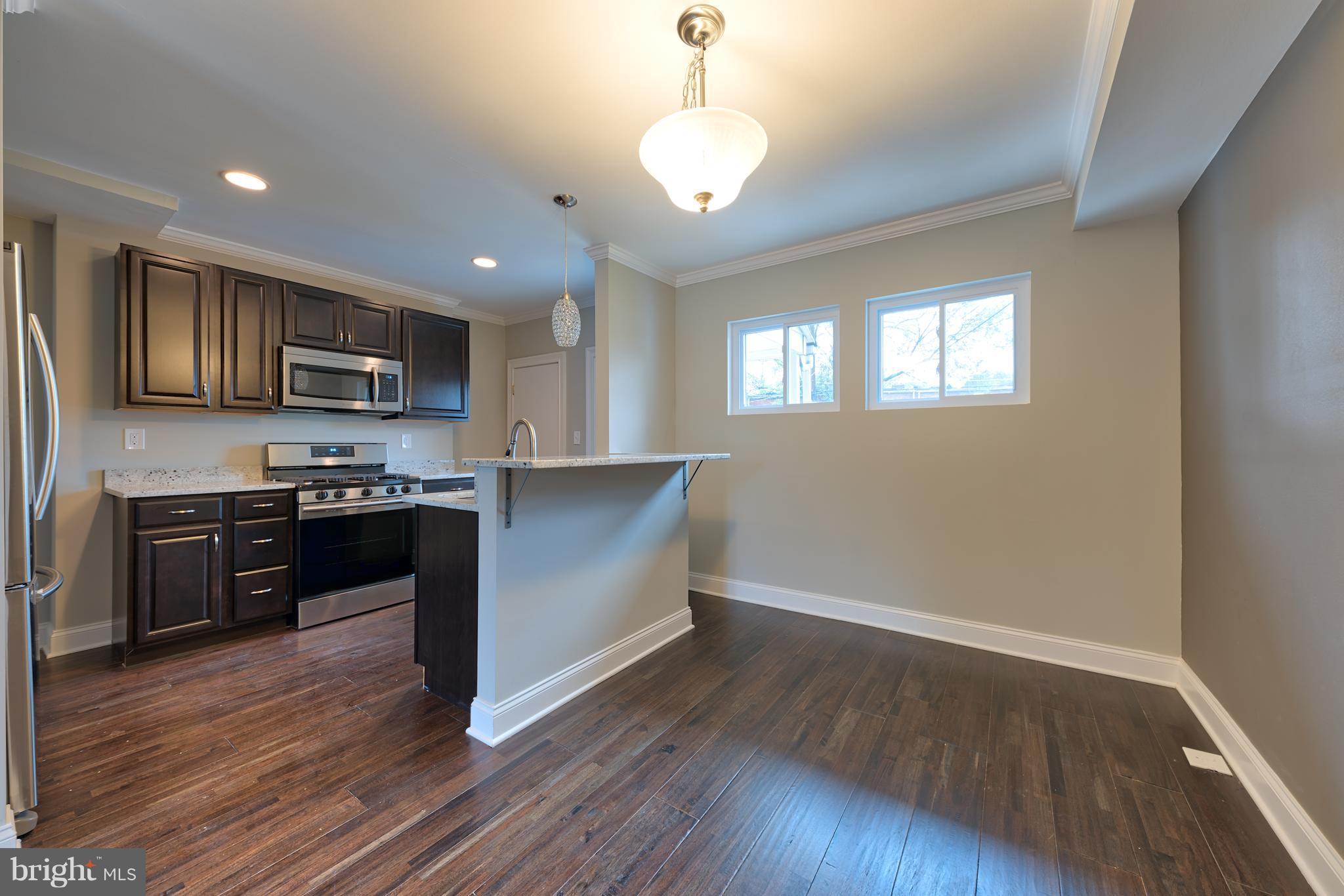 99 Willow Spring Road Baltimore, MD 21222 - Photo 2 of 30 a kitchen with granite countertop wooden floors stainless steel appliances and a window